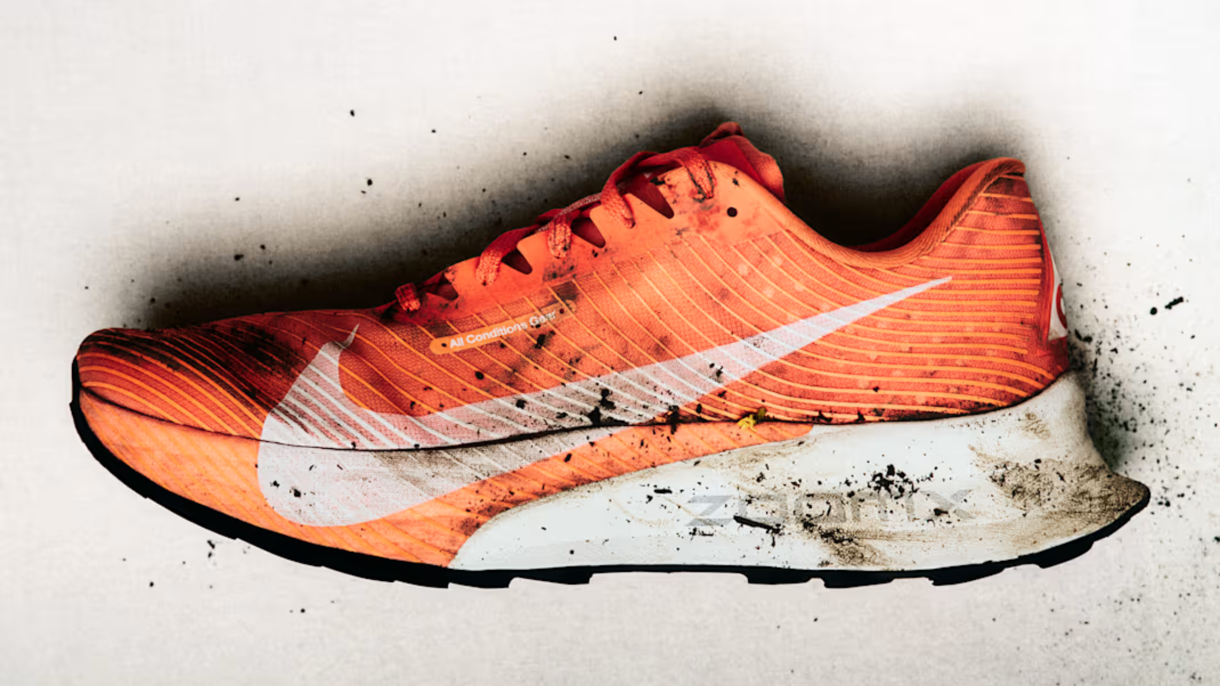 Mud-spattered bright orange Nike ACG Ultrafly trail shoe showcasing a white Swoosh and a dirty ZoomX foam midsole.